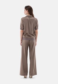 Braunes Satin-Oberteil mit kurzen Ärmeln und Kragen, kombiniert mit lockeren braunen Hosen. Glatte Textur, elastischer Taillenbund und dezenter Glanz.