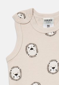 Béžový dětský overal bez rukávů s černobílými potisky lví tváře a patkami na rameni, velikost 56 EUR.