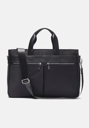 Sac fourre-tout synthétique noir avec deux poignées supérieures et une bandoulière réglable. Il comprend deux poches avant zippées et une texture lisse.