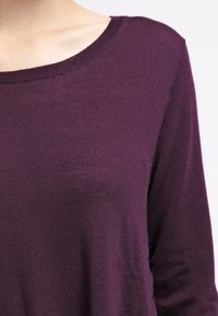 Pull léger de couleur violet profond avec un col rond et des manches longues. Le tissu semble doux avec une texture subtile.