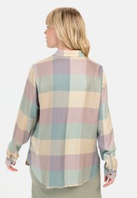 Button-up shirt in pastel plaid with soft, slightly glossy texture; features long sleeves, a rounded hem, and button cuffs.