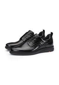 Scarpe in pelle nera con una finitura liscia, design slip-on, elastici e un sottile accento rosso sulla suola. Punta rotonda e collare imbottito.
