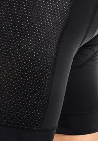 Pantalones cortos deportivos negros hechos de material que absorbe la humedad, con una textura perforada para transpirabilidad y costuras planas para mayor comodidad.