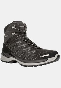 Botas de senderismo negras con parte superior de malla, puntera reforzada, acentos grises y un diseño con cordones. Presenta una superficie texturizada y suela resistente.