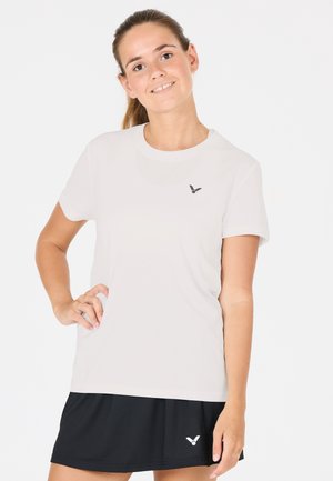 Hvid atletisk top med korte ærmer og rund halsudskæring samt et lille sort logo. Sammen med en sort nederdel med lagdelt design.