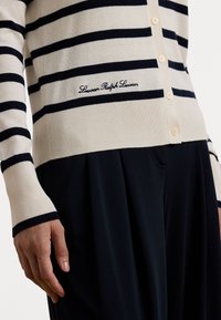 Beige cardigan with navy stripes, made of knit material. Features a button closure and embroidered "Lauren Ralph Lauren" logo at the hem.