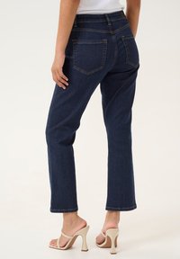 Jeans en denim bleu foncé avec une coupe droite, dotés de cinq poches, de coutures contrastées et d'une taille mi-haute.