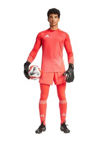 Uniforme de gardien de but en rouge vif, comprenant un maillot à manches longues avec un motif dégradé, des shorts assortis et des gants noirs. Ballon de football en main.