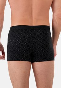 Schwarze Boxershorts mit einem gemusterten Design, das kleine Diamanten und Punkte zeigt. Der Gummibund ist einfarbig schwarz mit dezentem Branding.