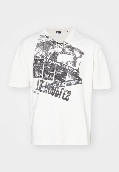 Valkoinen puuvillapaita, jossa on musta graafinen printti, jossa lukee "IKUISEN ELÄMÄN KIERTUE" ja "2008". Lyhyet hihat ja V-pääntie.