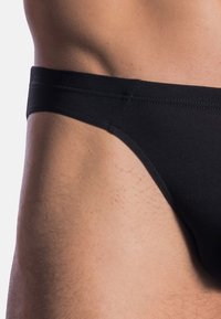 Black briefs made of smooth fabric, featuring a low-rise design and minimal seams for a clean appearance.