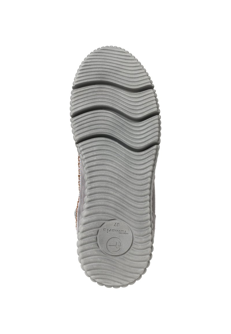 Schuhsohle aus strukturiertem grauem Gummi mit wellenförmigem Muster, rundem Logo-Abdruck und einem leichten Anstieg entlang der Kanten für besseren Halt.