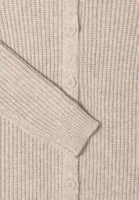 Neulecardigan vaaleassa beessissä, jossa on ribbikuvio. Ominaisuuksiin kuuluu viisi nappia ja rento istuvuus, joka korostaa pehmeää ja lämmintä materiaalia.