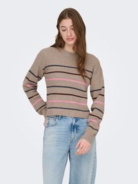 Pull en tricot couleur sable avec des rayures horizontales bordeaux, bleu marine et rose. Manches longues, texture côtelée, design court, porté avec un jean bleu clair.