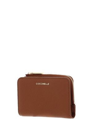 Portafoglio marrone in pelle con cerniera a giro e logo COCCINELLE dorato sul davanti.