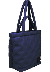 Quiltēts tumši zils somas iepirkumiem ar dubultām polsterētām rokturiem, ar kvadrāta formu un logotipa patch. Mīksta tekstūra ar gludu apdari.