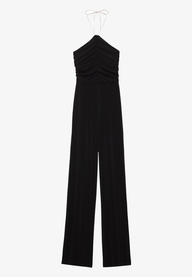 Combinaison noire sans manches à col halter avec buste froncé et pantalon à jambes larges, nouée au cou avec une fine lanière.