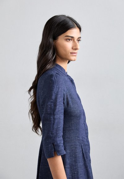 Navy blue linen dress with a collared neckline, three-quarter sleeves, and side slits. Textured fabric with a subtle pattern.
