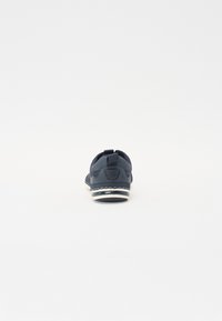Zapatilla de hombre en color azul marino con parte superior de malla, puntera redondeada, suela acolchada y costuras en contraste de color blanco. Lengüeta en el talón para facilitar el calzado.