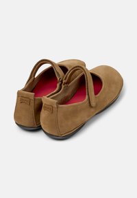 Scarpe Mary Jane in suede marrone con un interno morbido e due cinturini, che mostrano un design semplice ed elegante su uno sfondo neutro.