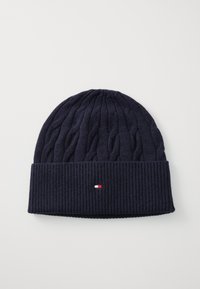Marine gebreide beanie met een gestructureerd kabelpatroon en een geribbelde boord. Heeft een klein logo in rood, wit en blauw op de boord.