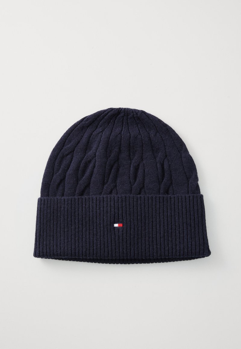 Marine gebreide beanie met een gestructureerd kabelpatroon en een geribbelde boord. Heeft een klein logo in rood, wit en blauw op de boord.