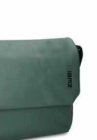 Borsa a tracolla impermeabile verde con logo "lamz" nero sulla patta anteriore.