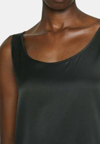 Top in raso nero con scollatura a barca, caratterizzato da una superficie liscia e cuciture minime ai bordi, che mette in risalto un design elegante e aderente.