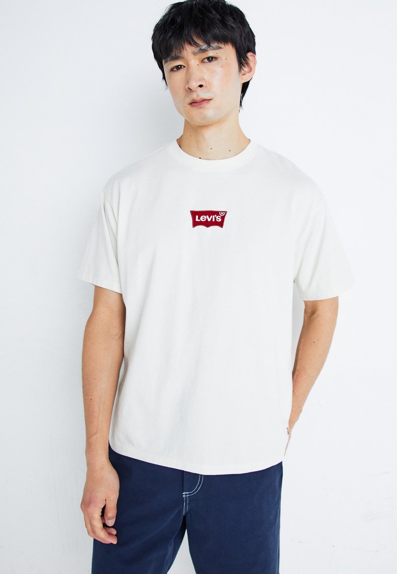 Balta medvilninė marškinėliai su raudonu Levi's logotipu ant krūtinės. Laisvas siluetas, trumpomis rankovėmis ir apvaliu kaklu. Išskirtiniai siuvimo akcentai.