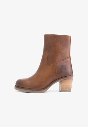 Bottine en cuir marron avec un bout arrondi, des coutures minimales, et un talon bloc avec une texture semblable au bois. Le logo est présent sur le côté.