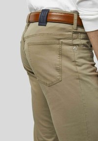 Beige Baumwollhosen mit glatter Textur, ausgestattet mit einem braunen Ledergürtel mit navy Etikett und zwei Gesäßtaschen mit gestickten Kanten.