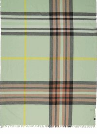 Manta de color verde claro con un patrón a cuadros en tonos gris, negro, rosa y amarillo, con bordes con flecos para añadir textura.