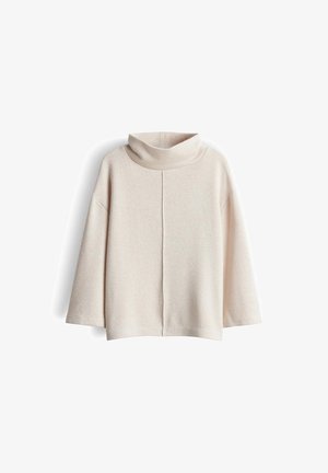 Romige oversized turtlenecktrui van zacht, textuurstof. Heeft een centrale naad en brede mouwen.