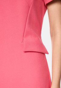 Figurbetontes rotes Kleid aus strukturiertem Material, mit einer einzigartigen Seitenfalte. Kurze Ärmel und ein glatter Abschluss werten das Design auf.