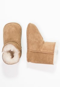 Botas de tobillo de ante marrón con suave forro de piel blanca, forma Curvada y detalles de costura visibles a lo largo de los bordes.