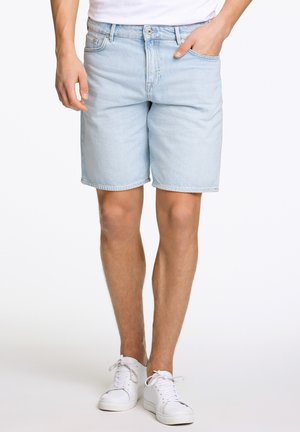 Lichtblauwe denimshorts met een rechte snit, vijf-pocket ontwerp en subtiele vervaging. Gecombineerd met witte sneakers.