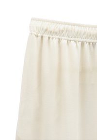 Spodnie z elastycznym pasem w kolorze off-white, wykonane z tkaniny o subtelnej, teksturowanej strukturze, z marszczeniami w talii umożliwiającymi regulację dopasowania.