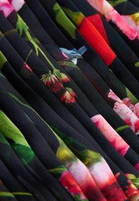 Lilleliseeline kangas elavate värvidega mustal taustal; sisaldab volte ja pehmet tekstuuri. Ideaalne rõivaste disainimiseks.