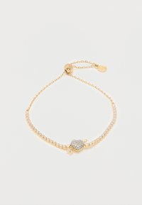 Λεπτό βραχιόλι με χρυσή αλυσίδα, διαφανή κρύσταλλα και ένα κεντρικό μενταγιόν σε σχήμα μήλου διακοσμημένο με μικρές λαμπερές πέτρες.