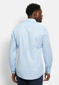 Himmelblaues Langarmhemd aus glattem Stoff, mit einem klassischen Kragen, geknöpften Manschetten und einem abgerundeten Saum hinten.