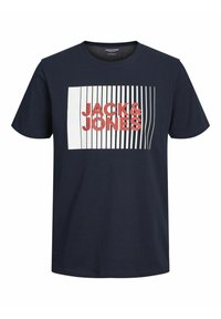 Tumši zilas krāsas kokvilnas T-krekls ar īsām piedurknēm. Tam ir balts taisnstūrveida grafiskais attēls un sarkans uzraksts "JACK&JONES" ar vertikālu līniju rakstu.
