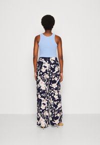 Jasnoniebieski top na ramiączkach w połączeniu z granatowymi spodniami szerokimi w kwiaty w kremowy i różowy wzór, miękka tkanina i luźny krój.