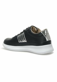 Black sneaker featuring textured leather, silver accents, perforated detail, and a white rubber sole. Classic lace-up design.