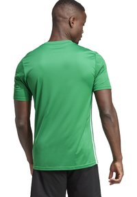 Maglietta sportiva verde realizzata in un materiale liscio e traspirante, con maniche corte, strisce laterali bianche e un fit rilassato.