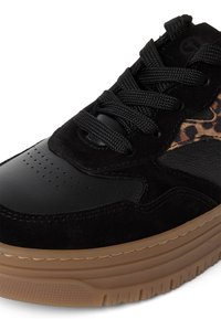 Baskets noires avec bout en cuir texturé, détail latéral imprimé léopard, semelle épaisse en caoutchouc marron et lacets noirs en gros plan.