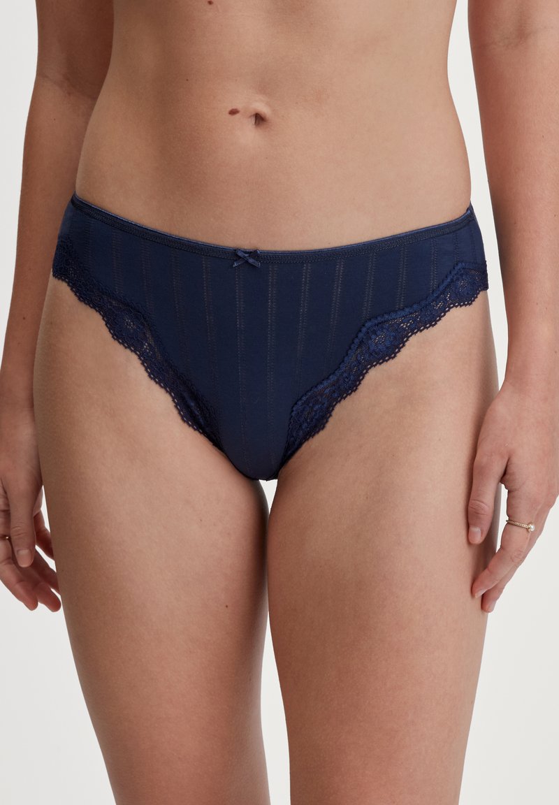 Marineblauwe onderbroek met kantafwerking, verticale strepen en een klein strikdetail aan de voorkant. De stof lijkt glad met een lichte glans.