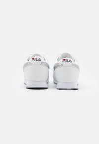 Baskets blanches avec accents gris, bout arrondi, semelle rembourrée et logo "FILA" à l'arrière. Cuir lisse et matériau textile.