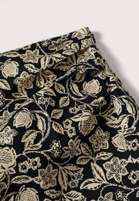 Tela negra con un dibujo de flores y hojas en color beige, con detalles intrincados y una textura suave.