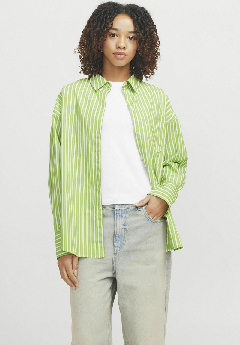 Striped, long-sleeve shirt in light green and white, featuring a button-up front, relaxed fit, and a breast pocket. Paired with light denim jeans.