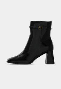 Mustmust mustatooted, millel on terav nina, plokk konts ja kullast klamber ühel rihmal ümber pahkluue.